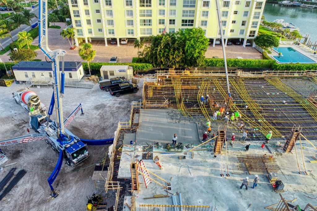 Aerial drone photography in Fort Myers, FL of a construction site with the foundation being laid and a crane bringing materials to the site